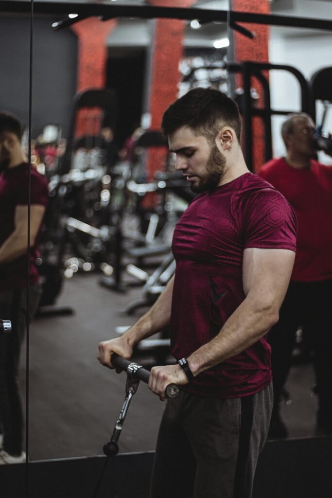 Young Handsome Man in Sport Shirt Doing Workout in Fitness Gym