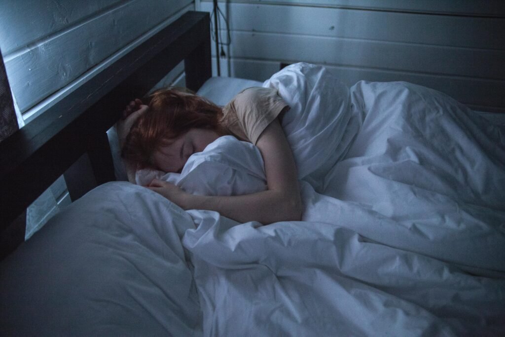 A woman sleeping peacefully in a cozy bedroom, enveloped by soft white sheets, under the gentle glow of night light. Rest days