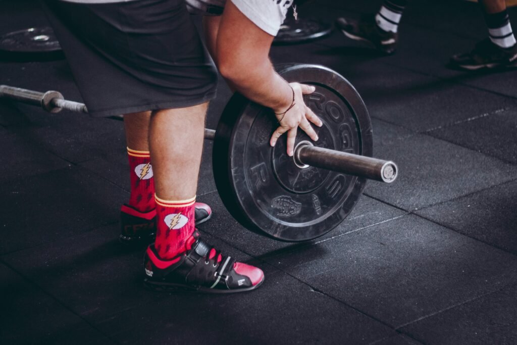 A man prepares to lift a barbell on the gym floor, demonstrating strength and fitness.