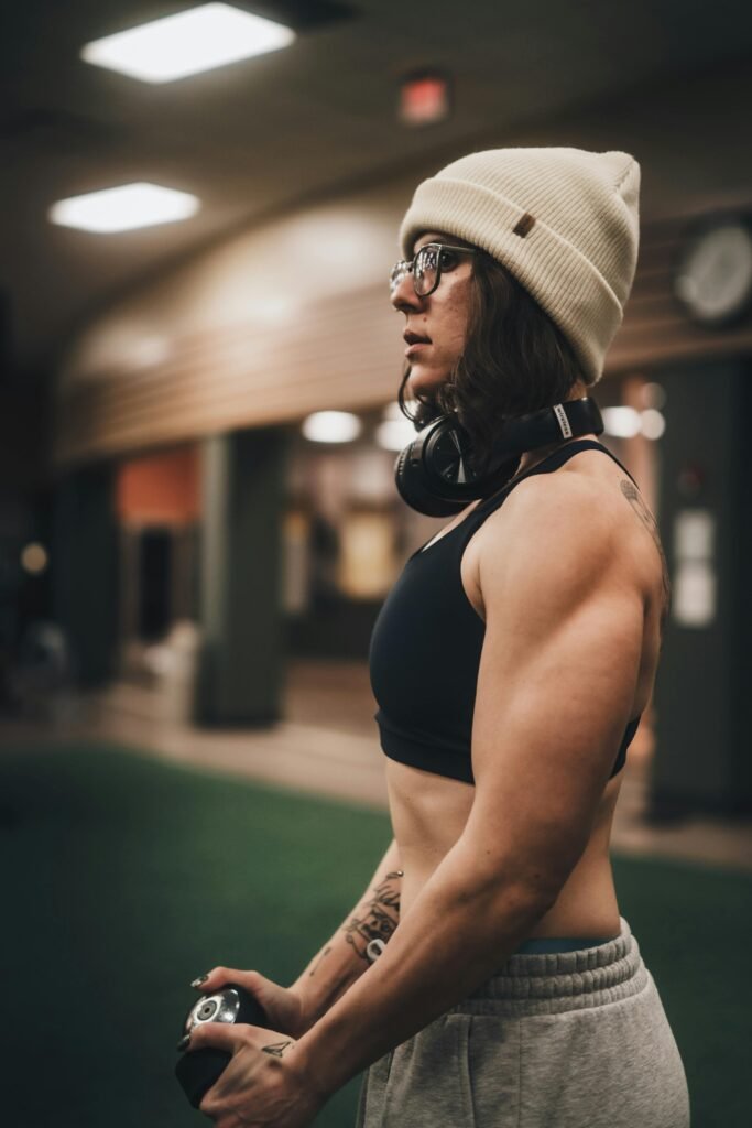 A determined female athlete in a gym, wearing a beanie and headphones, ready for a workout.