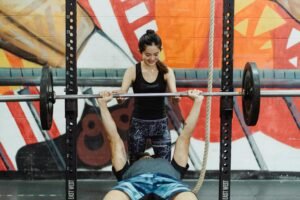 Asian couple engaged in fitness training at the gym, bench press exercise.