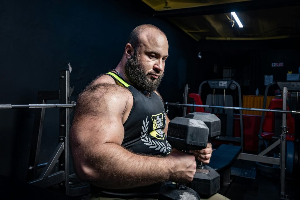 Strong bodybuilder lifting heavy dumbbells in a gym setting, showcasing strength and power.