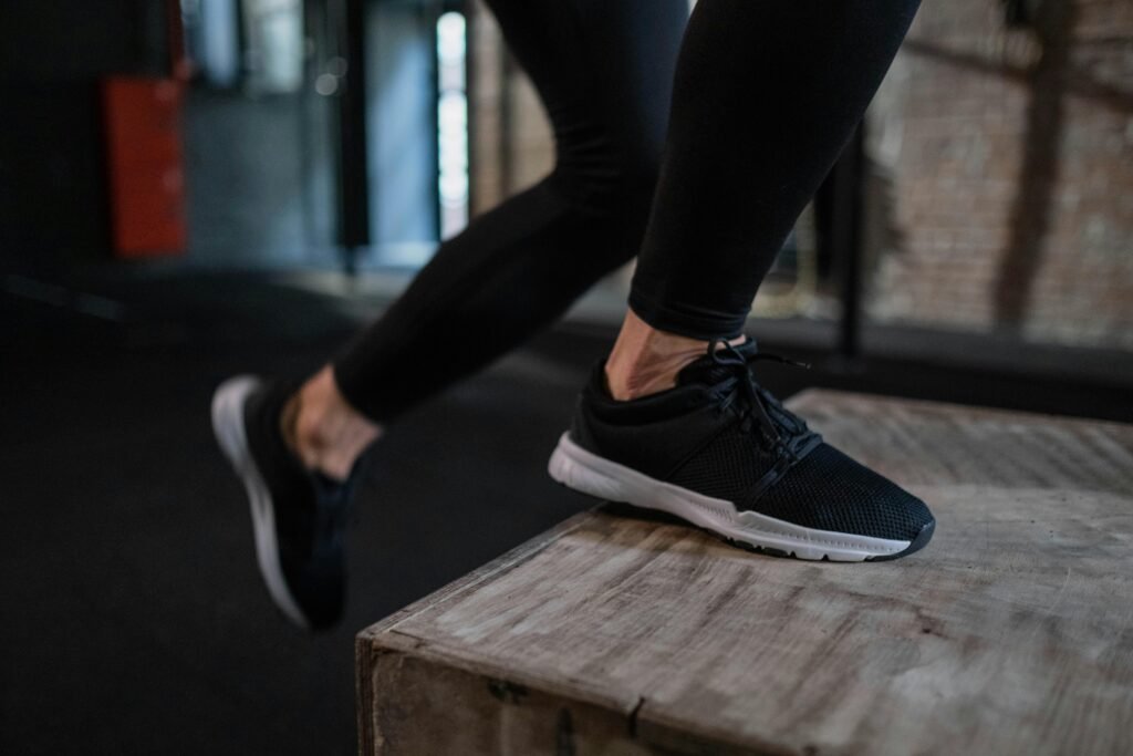 pexels-photo-7675403-7675403 Close-up of an athlete's legs performing a box jump indoors, showcasing athletic footwear and activewear. The Benefits and Science of Joint and Tendon Stiffness in Athletic Performance