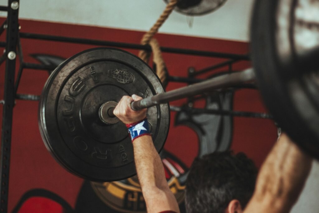 Athlete lifting heavy barbell during strength training session in gym. High Volume vs. Low Volume Training: How to Program Smarter for Long-Term Gains