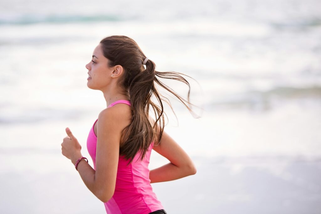 pexels-photo-1199590-1199590 Side view of a young woman jogging on a beach wearing pink active wear. 5 Best Affordable Women’s Workout Tops That Don’t Ride Up