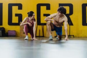 A man and woman in a gym exercising, showcasing fitness, health, and happiness.