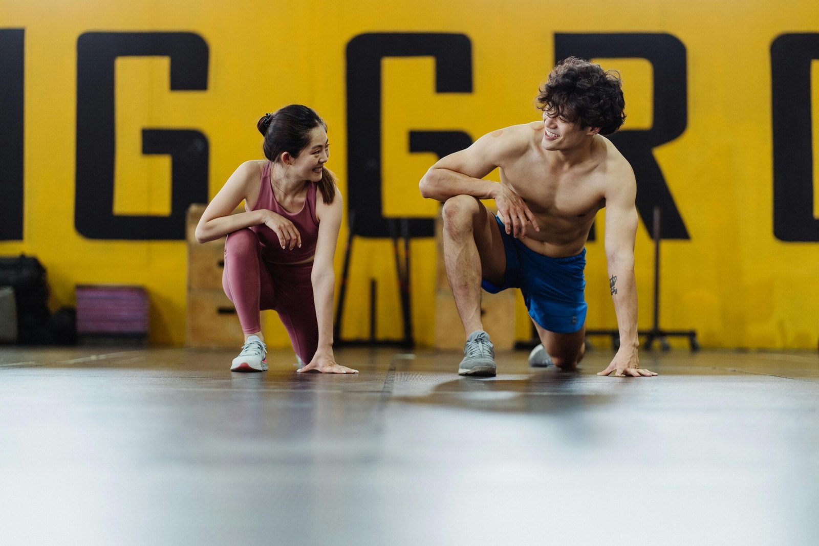 A man and woman in a gym exercising, showcasing fitness, health, and happiness.