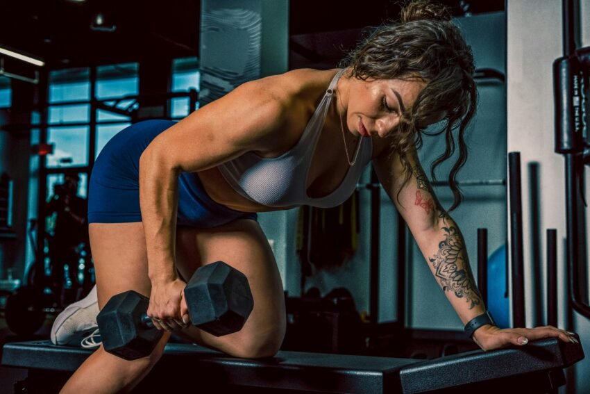 Focused woman lifting dumbbell for gym training. Intense and powerful workout session.