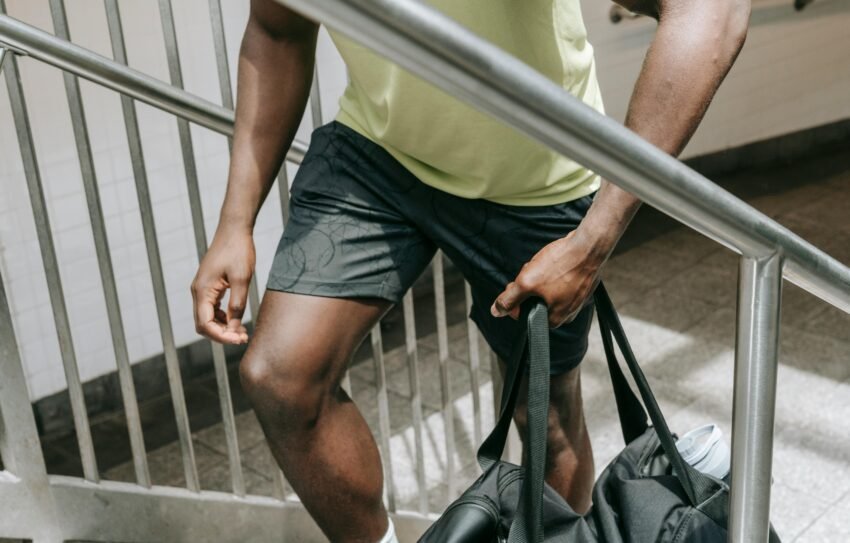 Man in athletic wear carrying a gym bag up a stairway, emphasizing fitness lifestyle.